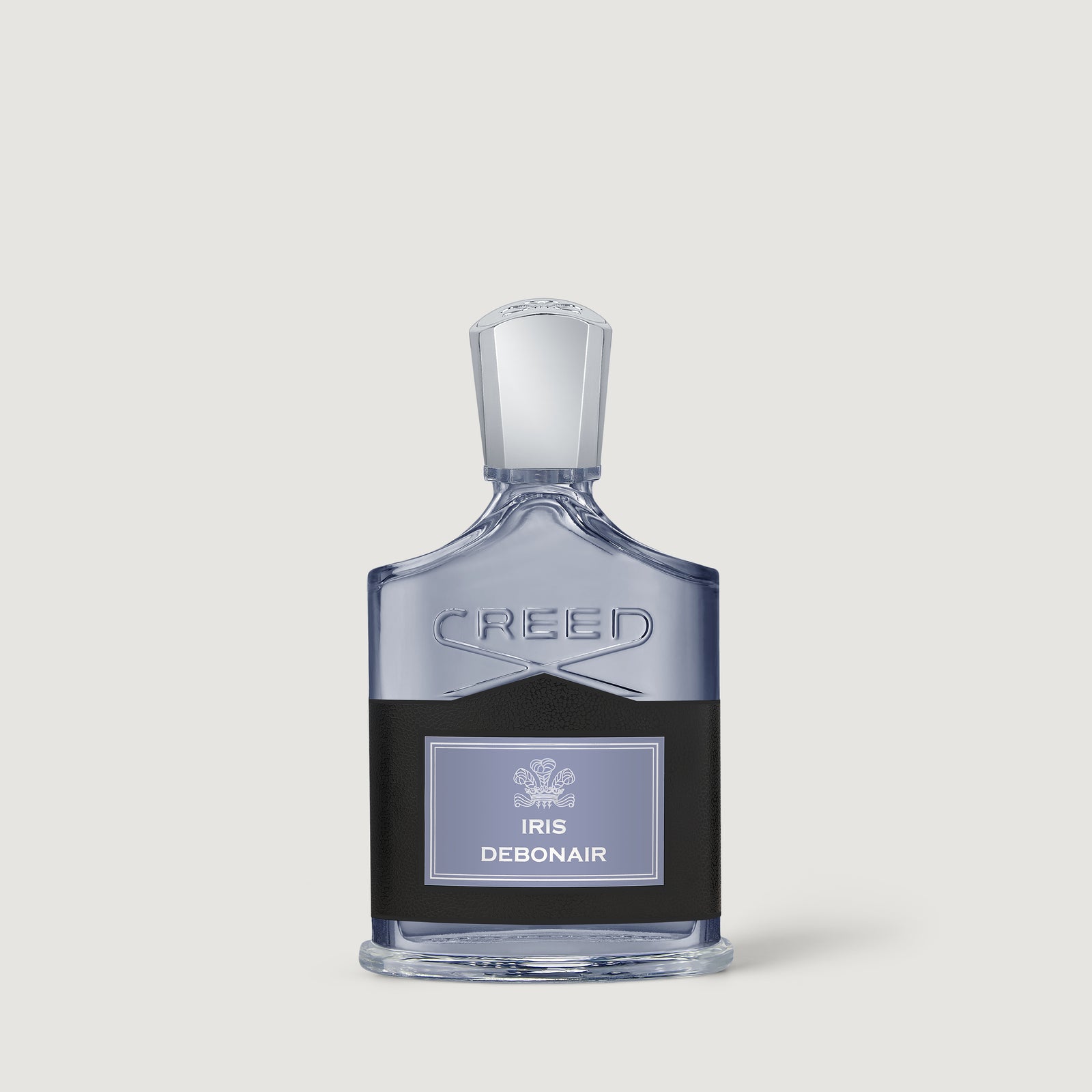 A pale grey bottle of Creed Iris Debonair with a black leather wrap against a warm grey background.